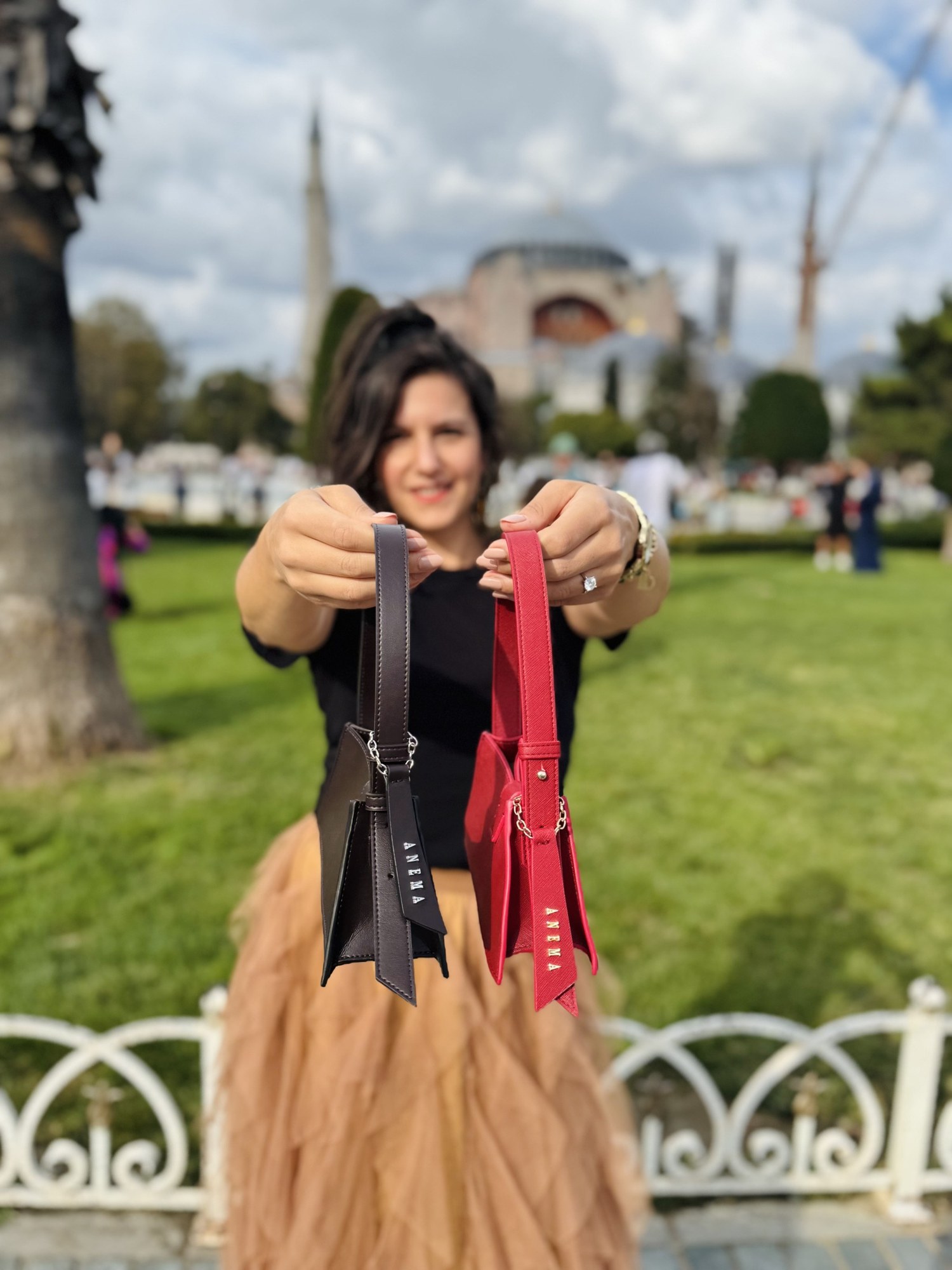 Benedetta con due borse, marrone e rossa, davanti a una moschea